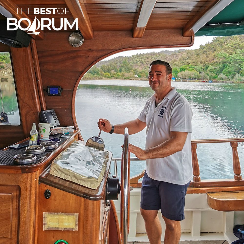 The captain, Gursel, of a traditional Turkish wooden sailboat (gulet) smiling at the camera while sailing in Gokova.