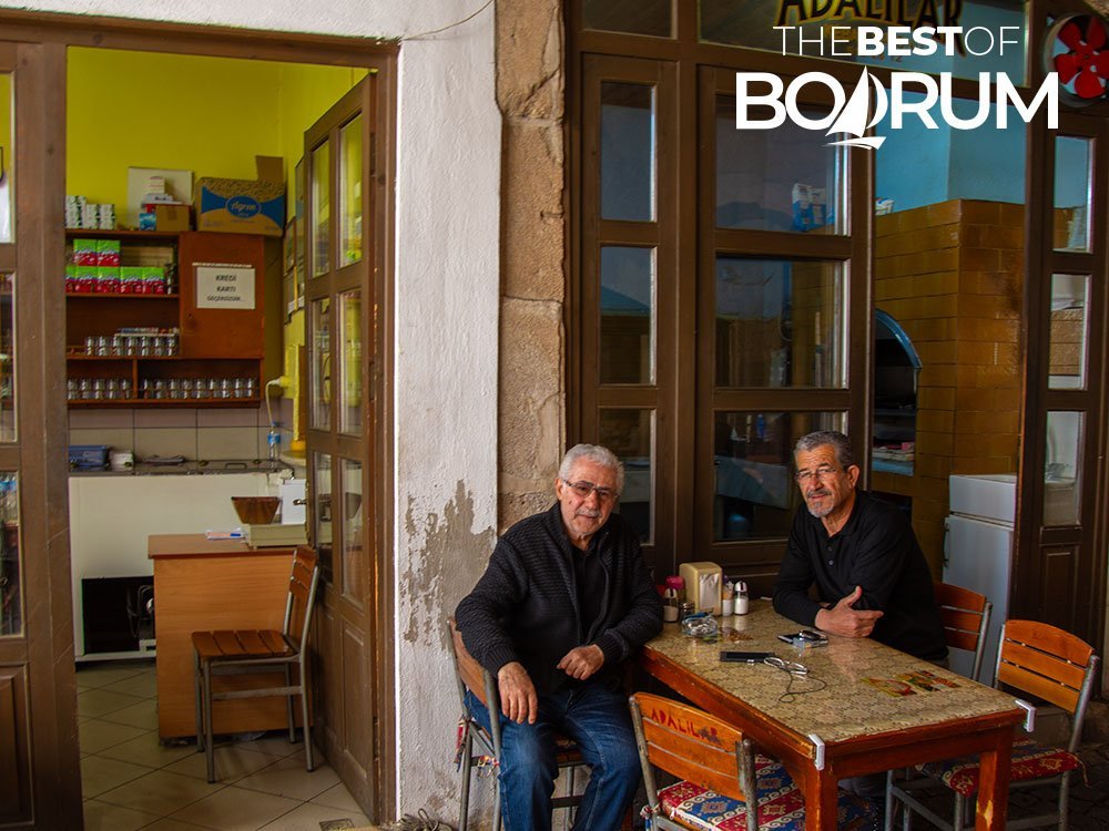 Two men, owners of a traditional meatball restaurant, sitting and posing for the camera in Milas.