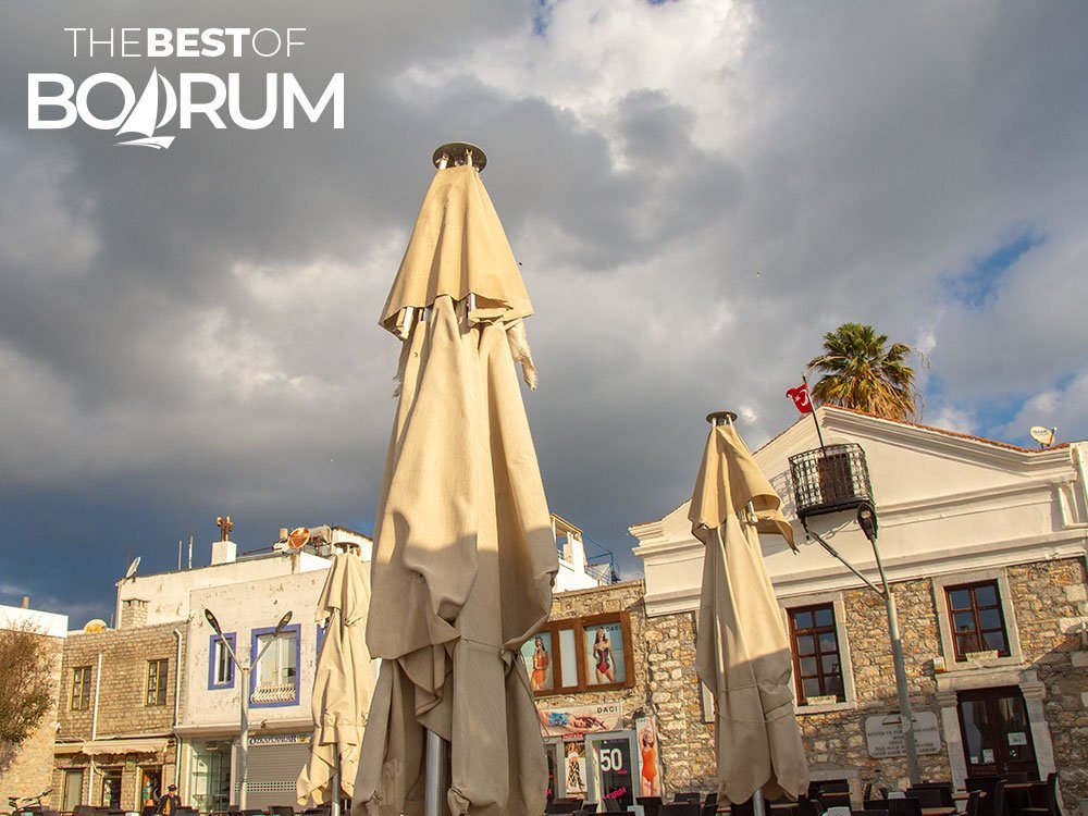 Old stone houses, dark clouds and sunlight in winter in Bodrum.