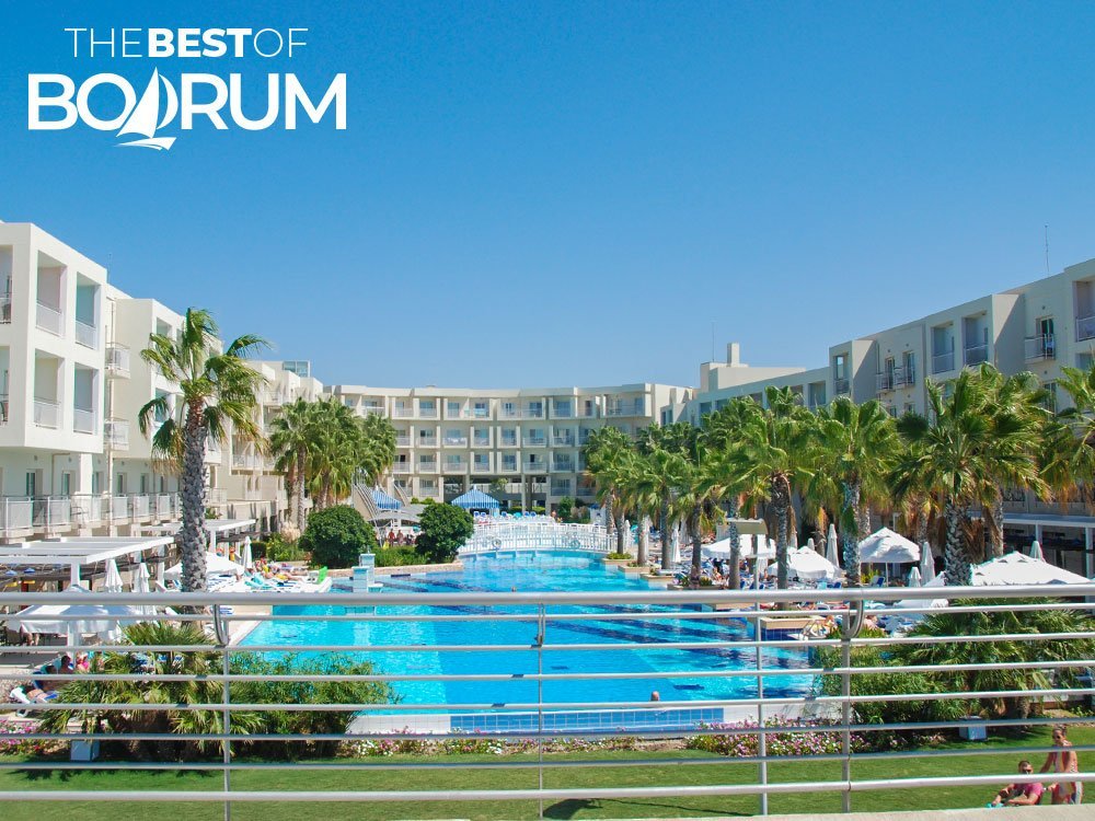 A clear blue sky overlooking a hotel pool in Turgutreis during autumn. The pool is surrounded by lounge chairs and umbrellas, signalling the end of the season.